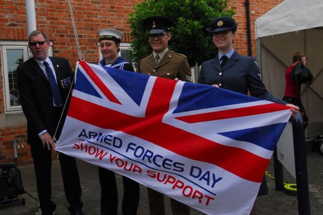 NKDC facilities officer Steve Evans raising the flag with armed forces representatives. EMN-190625-125855001