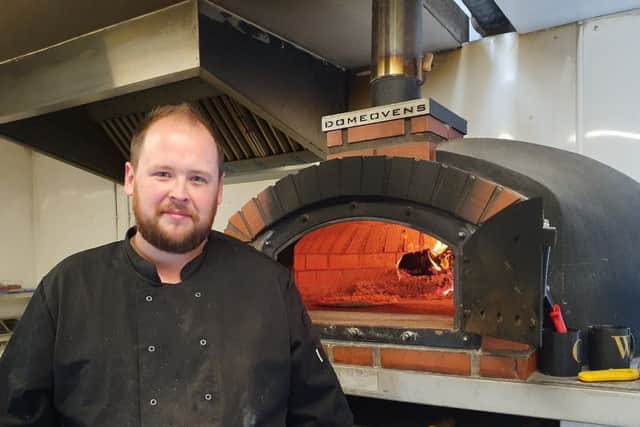 Scott Adam stands proudly beside the oven at The Wood Shed Pizza.