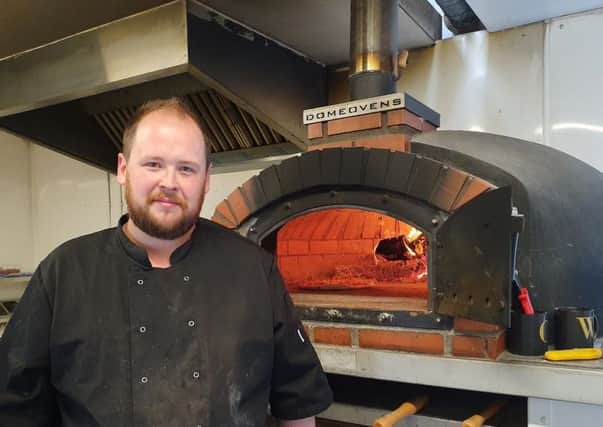 Scott Adam stands proudly beside the oven at The Wood Shed Pizza.