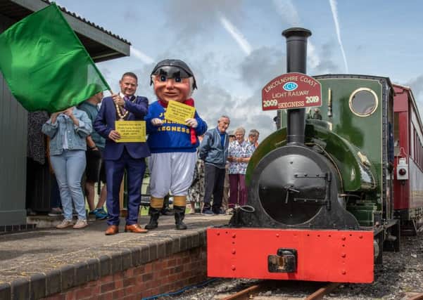 The Mayor of Skegness, Coun Mark Dannatt, with the Jolly Fisherman - with their giant commemorative tickets - waves the guard's flag to give the 'right away' to the Anniversary Special train at Walls Lane station. (Photo: Dave Enefer/LCLR)