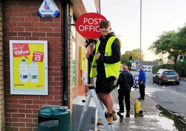 A worker installs the Post Office sign outside the Spar shop in Sutton on Sea. (Photo: Adrian Benjamin).