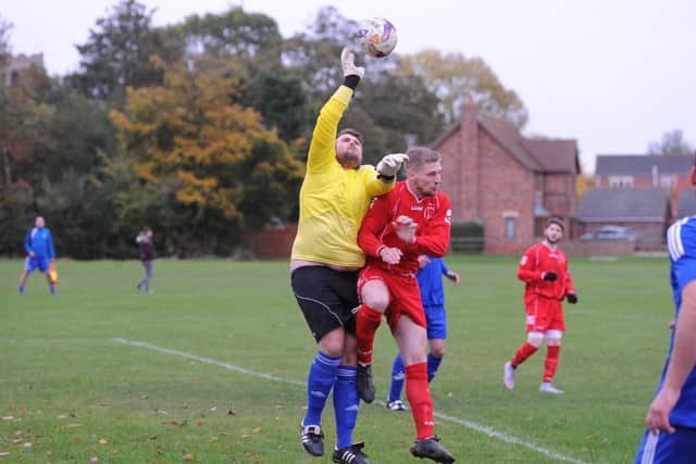 Fishtoft keeper Liam Brooks outjumps Swineshead's Richard Barker.