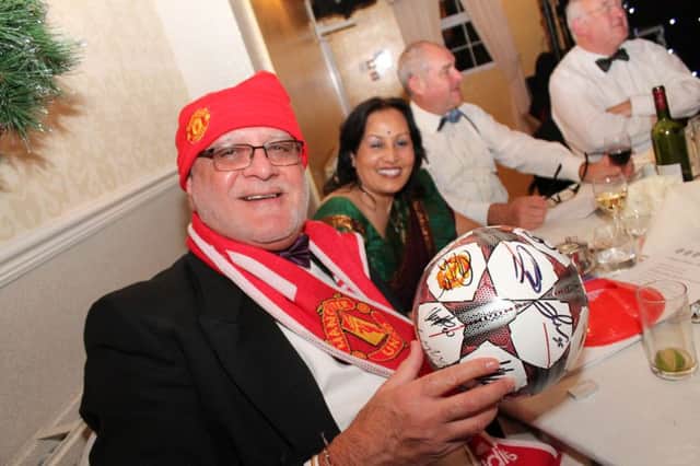 Pictured is Jagdish Dhanak celebrating his auction prize of the Manchester United signed ball, scarf and hat.