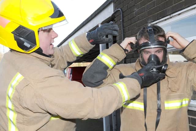 Firefighter Richard Wainwright helping Luke Burns, of Skegness, put on a training mask.