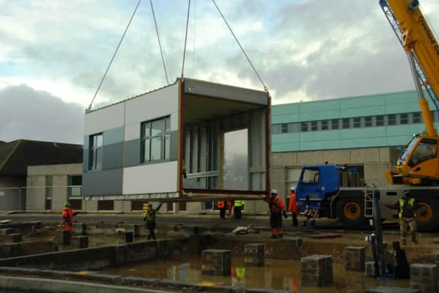 Construction staff manouver the new maternity units into place.