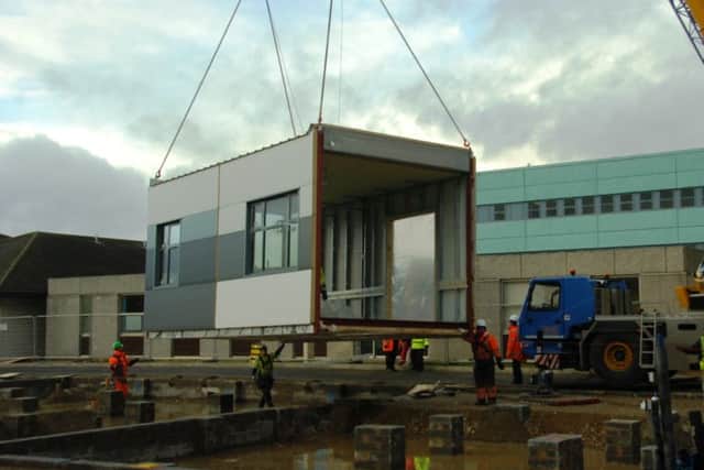 Construction staff manouver the new maternity units into place.