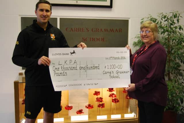 PE teacher Russell Smith, presents funds raised by a sponsored walk by Carre's pupils to Anne Carter of LKPA. EMN-160605-174259001