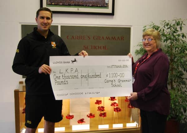 PE teacher Russell Smith, presents funds raised by a sponsored walk by Carre's pupils to Anne Carter of LKPA. EMN-160605-174259001