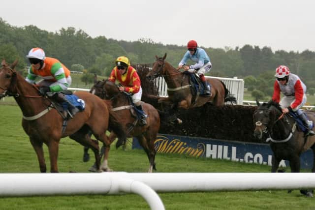 Runners in the 32 Red.Com Handicap Chase take a fence. Local horse Tayarat, trained by Michael Chapman, is in orange and gold EMN-160526-092852002
