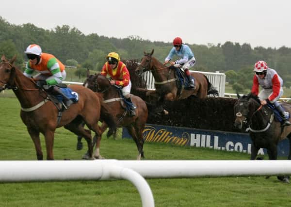 Runners in the 32 Red.Com Handicap Chase take a fence. Local horse Tayarat, trained by Michael Chapman, is in orange and gold EMN-160526-092852002
