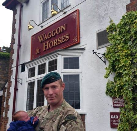 Sergeant Matt Harness cradles his son Spencer in the car park of the Waggon and Horses pub in rural Lincolnshire.
