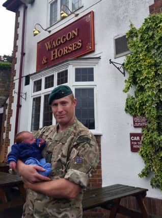 Sergeant Matt Harness cradles his son Spencer in the car park of the Waggon and Horses pub in rural Lincolnshire.