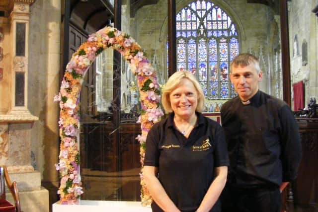 Interflora floristry display team member Janet Boast from Nelson in Lancashire and Rev Phillip Johnson with the floral arch on display. EMN-160624-170127001