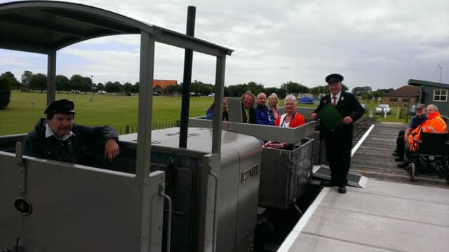 Volunteer Chris Bates waves the flag to allow the first passengers to experience a ride on a renovated WW1 wagon at the Lincolnshire Coast Light Railway. ANL-160713-172144001