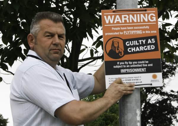 Coun Richard Wright pictured with a fly tipping sign. EMN-161107-184223001