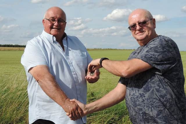 Metal-detectorist Charlie Atkinson hand sthe medal over to Basil Bruntlett