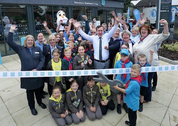 Callum Beeching (6) cuts the ribbon to open the store watched by store staff and Beavers, Brownies, Cubs, Scouts and Leaders from the 1st Hibaldstow and Scawby group.
 ? Tim George/ UNP 0845 600 7737

Co Op 35341 Hibaldstow EMN-160826-083211001