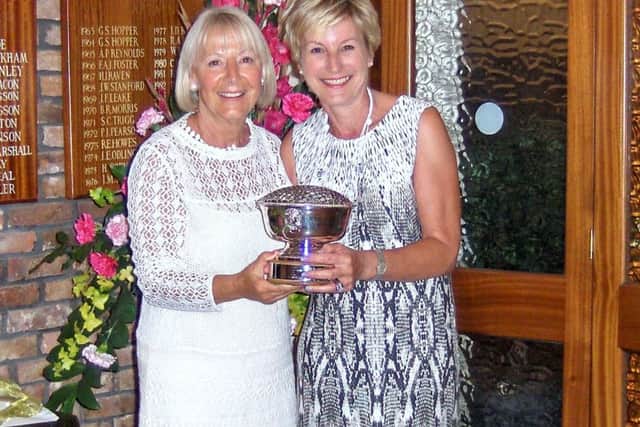 Anne Wallhead is seen presenting the Lady Captain's Rose Bowl to Judith Flevill (right).