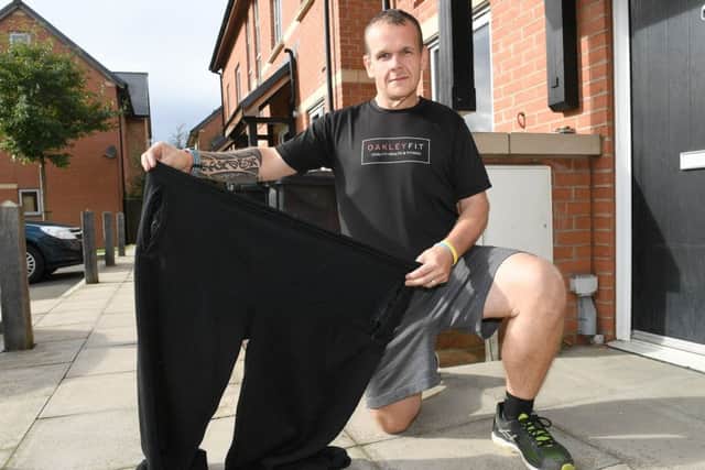 Chris Degnan with trousers he used to wear before losing 14st. EMN-161010-101456001