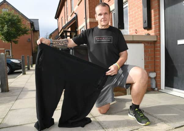 Chris Degnan with trousers he used to wear before losing 14st. EMN-161010-101456001