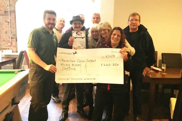 Micky Moon (centre) with friends and supporters, and the cheque for Macmillan Cancer Support. EMN-161211-151626001