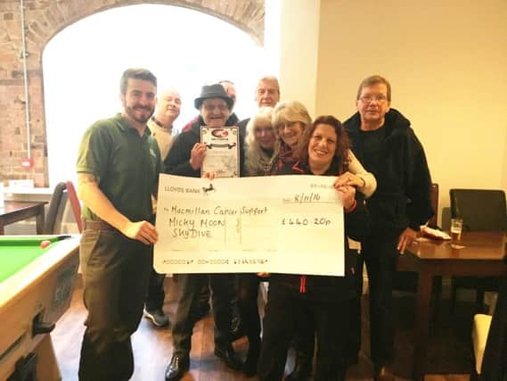 Micky Moon (centre) with friends and supporters, and the cheque for Macmillan Cancer Support. EMN-161211-151626001