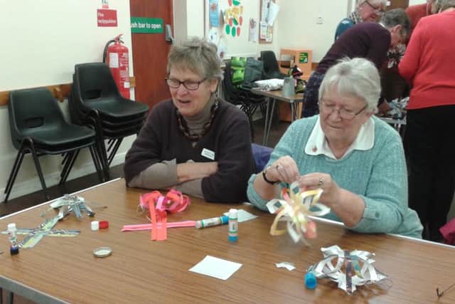 Pictured is Chris Morgan watching while Jane Riggall demonstrates how to make a Finnish star.