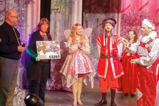 Muddles played by Mike Carnell presenting a cheque to ward sister Margaret Goodley on stage. EMN-171201-172005001