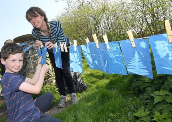 Sleaford heritage trail family arts activities at The Nettles. Sam Lawrance 7 with Lucy Lumb of ArtsNK, hanging up his Cyanotype sunlight prints. EMN-170414-153413001