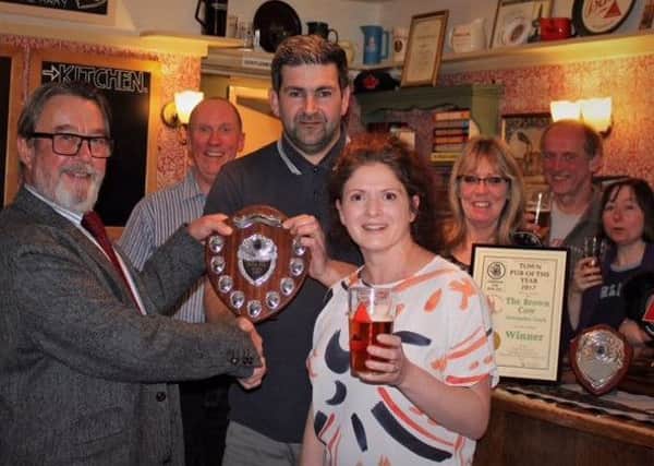 Pub owners Nigel and Victoria Hooper (centre), pictured accepting the award from outgoing chair Melvin Mullens.