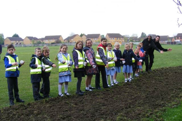 Pupils of St Botolph's and Our Lady of Good Counsel schools scatter wild flower seeds at Woodside play area with Town Council staff Sam White and John Green. EMN-170424-181445001