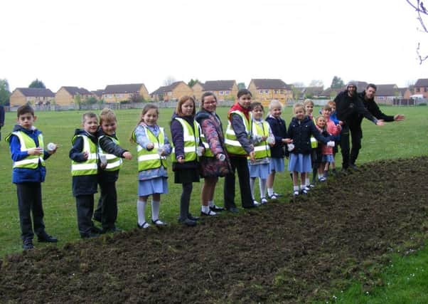 Pupils of St Botolph's and Our Lady of Good Counsel schools scatter wild flower seeds at Woodside play area with Town Council staff Sam White and John Green. EMN-170424-181445001