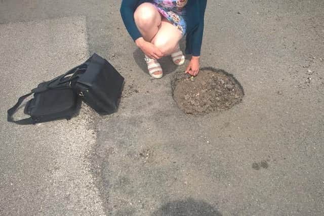 A motorist stops to examine a pot-hole which her car ran into in Horncastle .