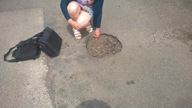 A motorist stops to examine a pot-hole which her car ran into in Horncastle .