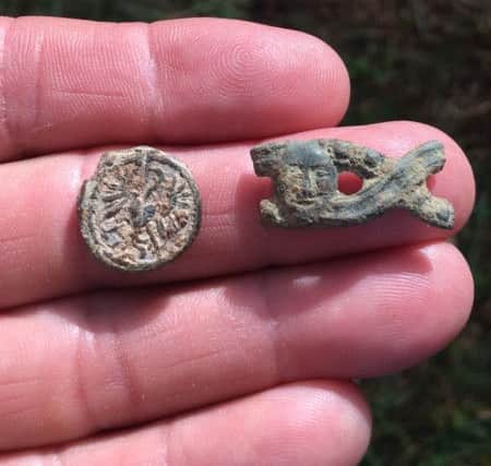 A coin and metal purse clasp with ornate 'face' detailing - both unearthed by Mr Drayton, who dated them to the King John era.