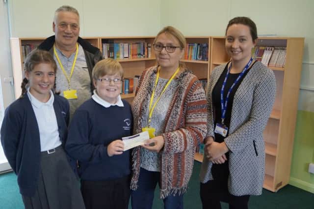 Christine Smith and Bishop Goodyear hand over the money to pupils Adam Bates and Lara Buck, and teacher Chloe Walford, who is leading the library refurbishment EMN-170610-061324001