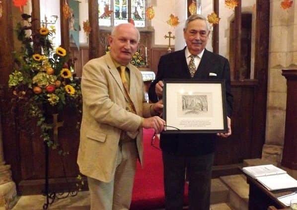 John Bangay presents the commemorative Gertrude Reed drawing to churchwarden Trevor Bush during Sundays harvest festival service inthe church.